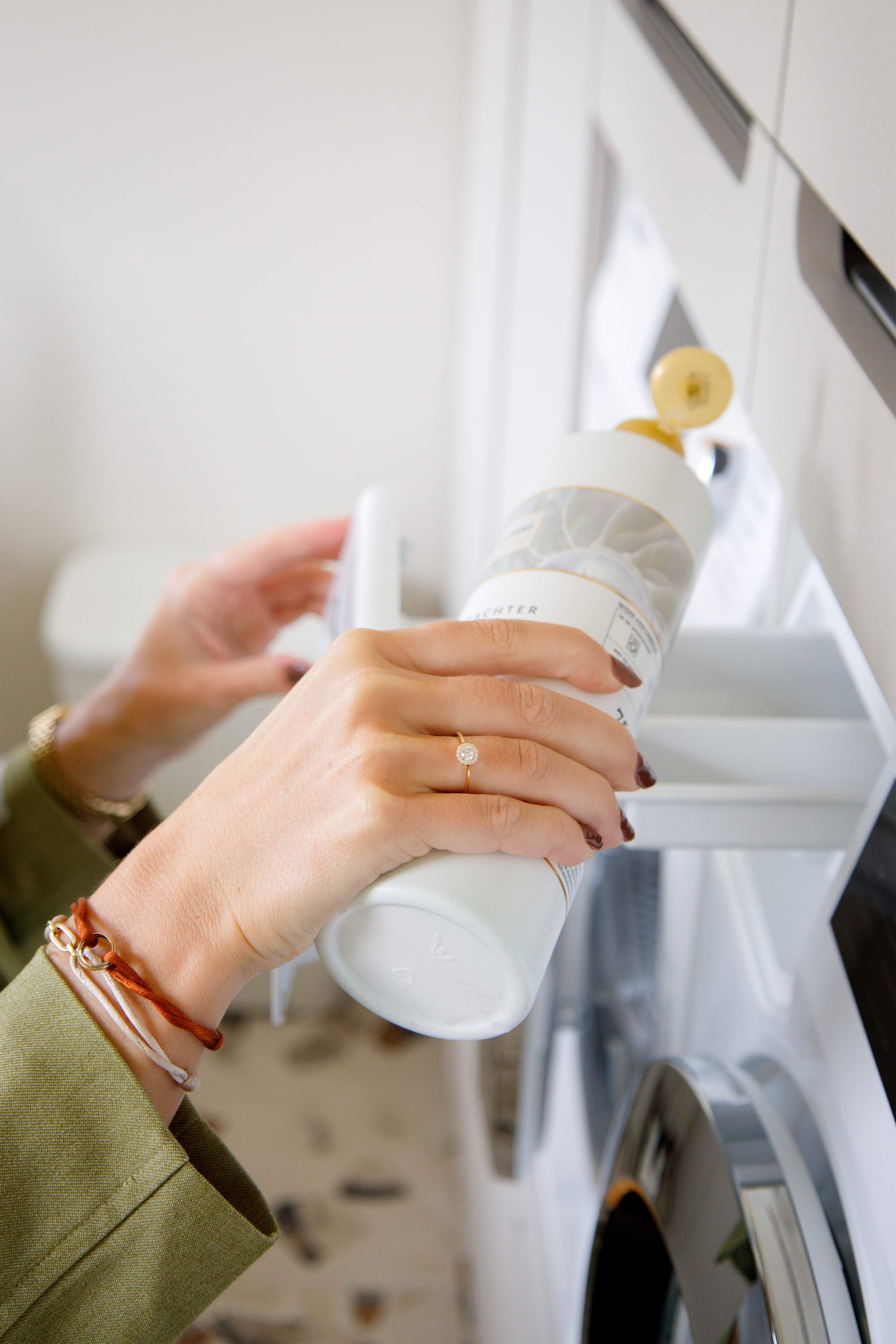 Vrouw giet wasparfum in wasmachine